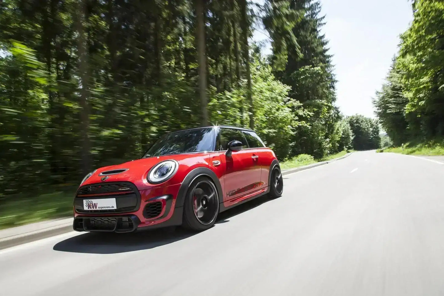 Roter Mini John Cooper Works F56 mit Tuning-Teilen fährt auf Landstraße im Grünen