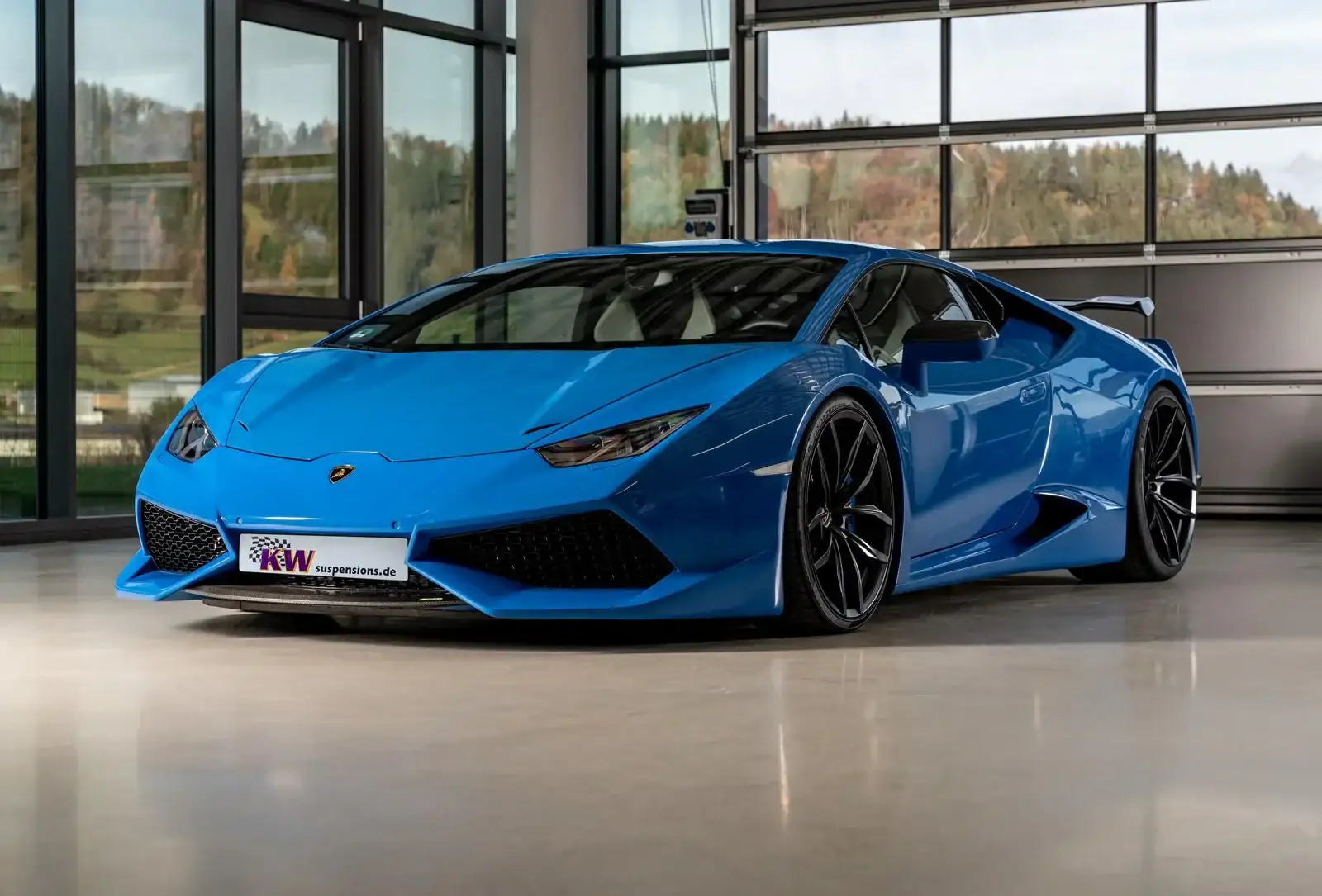 Blauer Sportwagen mit auffälligen Tuning-Teilen, tiefergelegt, in moderner Garage bei Tageslicht