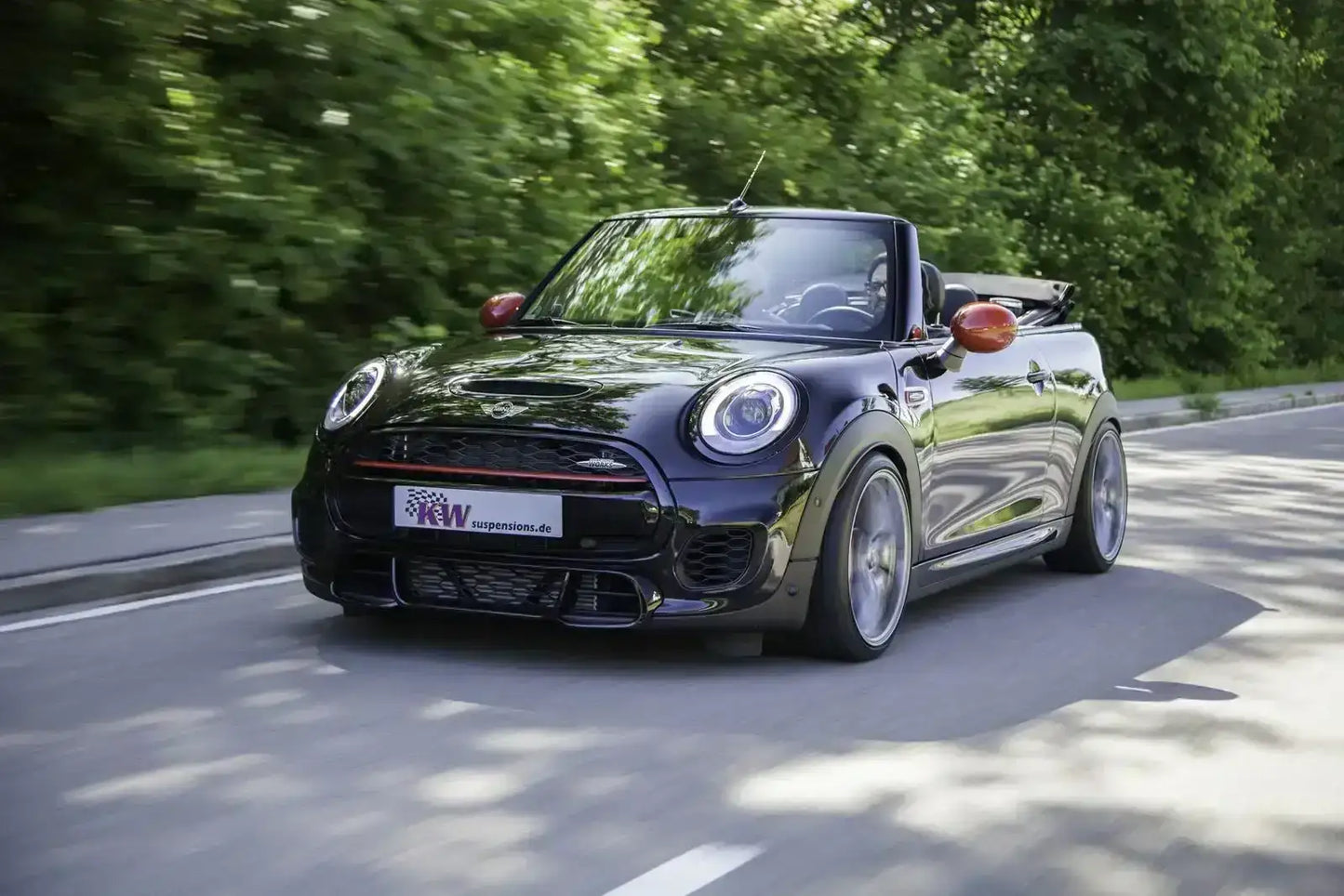 Schwarzer Mini John Cooper Works Cabrio mit Tuning-Zubehör fährt auf Straße, KTH Shop
