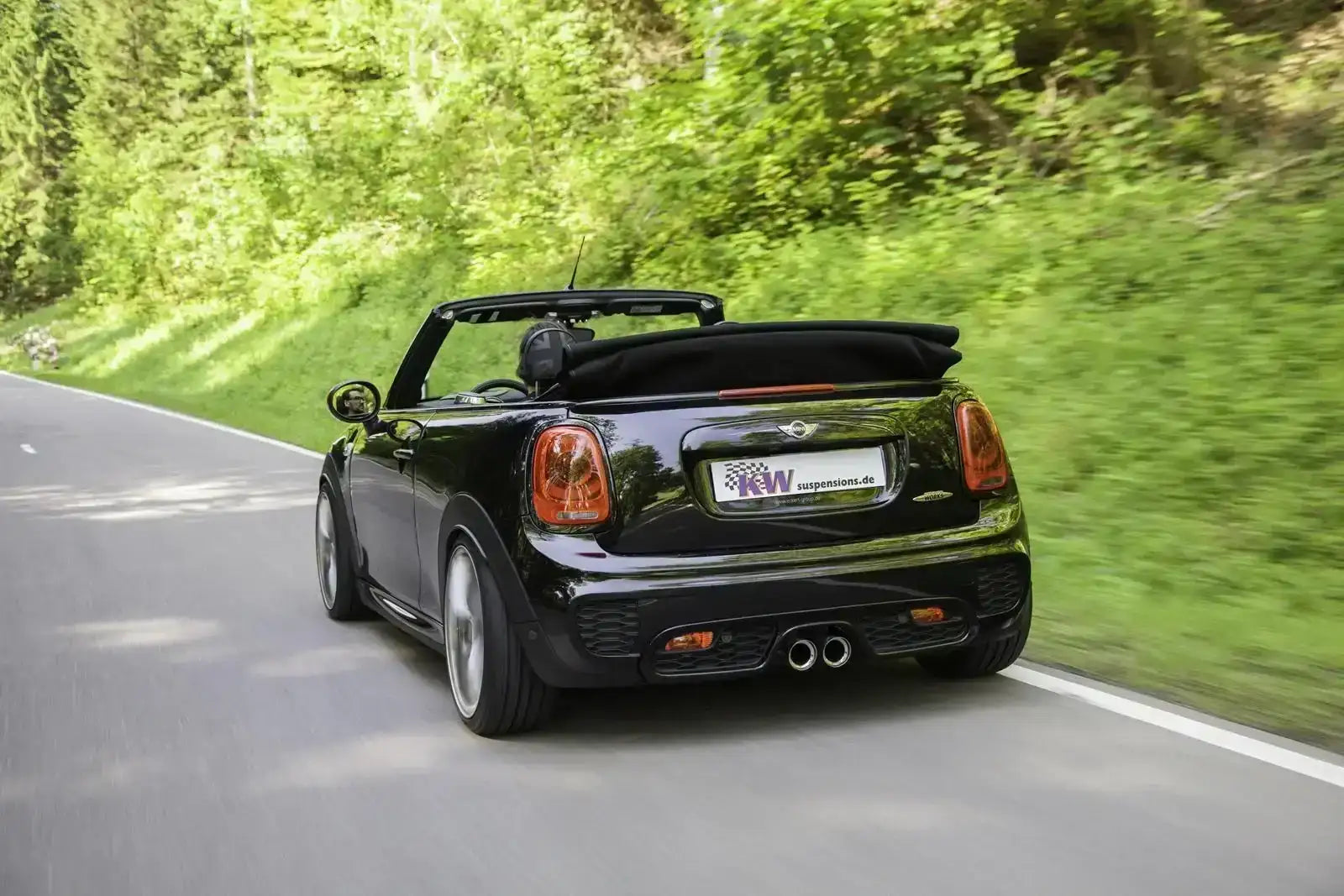 Schwarzer Mini John Cooper Works Cabrio fährt auf Landstraße, Tuningteile KTH Shop, Sommer