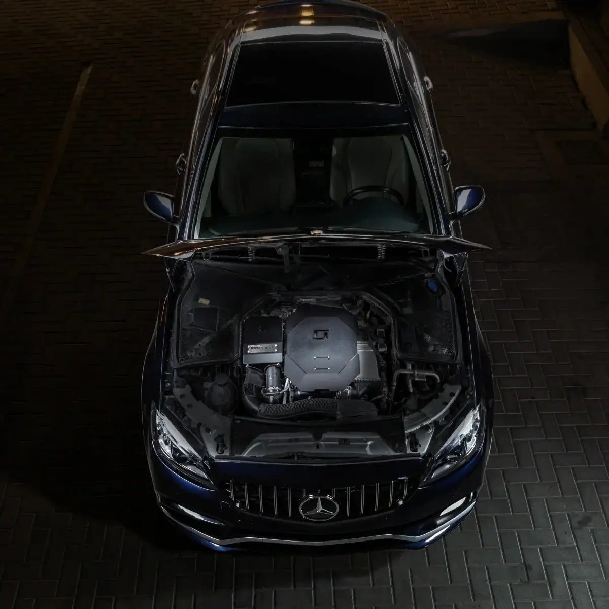 Mercedes mit offener Motorhaube, hochwertiges Tuning-Teil im Motorraum auf Pflaster